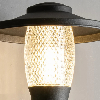 Illuminated black metal and glass sconce casting warm ambient light on wall