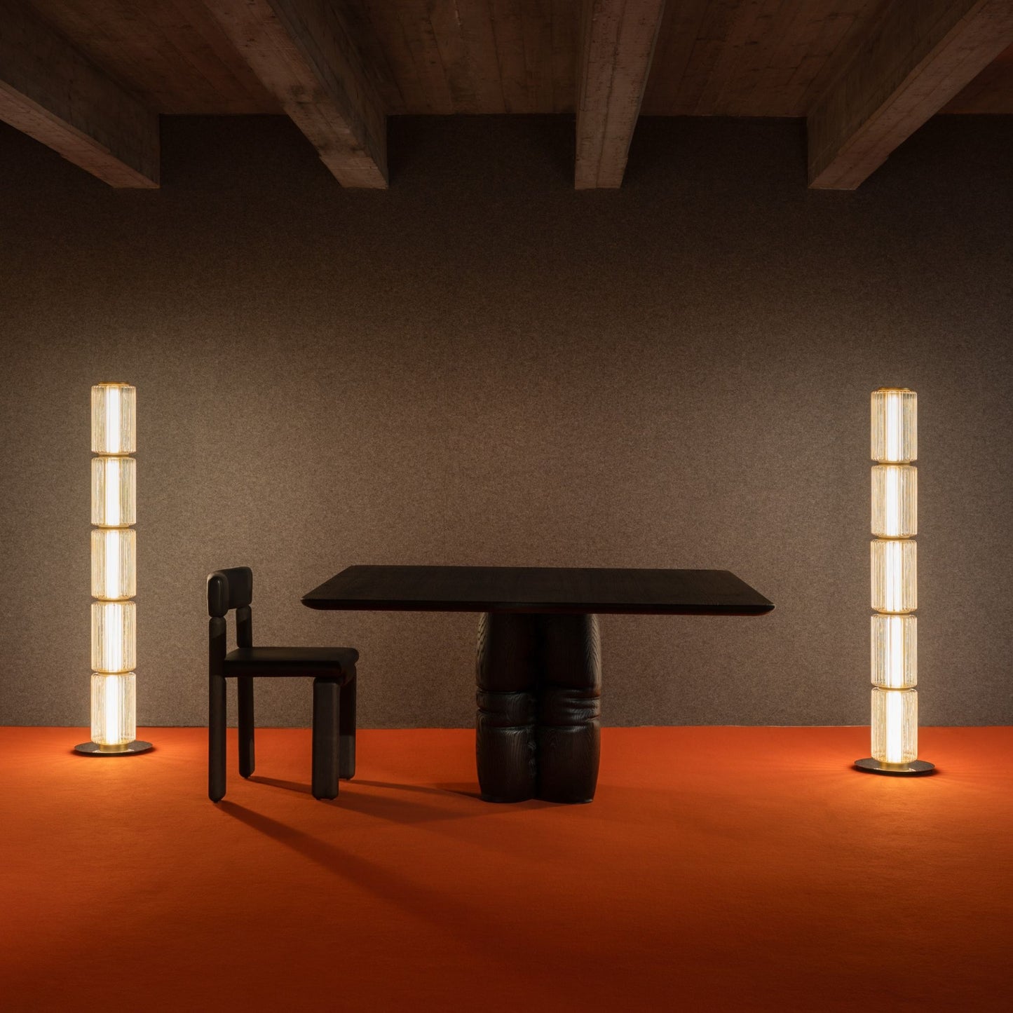 Group of tall ribbed-glass floor lamps creating soft ambient light in a dark, modern room with an orange floor.