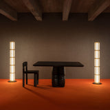 Group of tall ribbed-glass floor lamps creating soft ambient light in a dark, modern room with an orange floor.