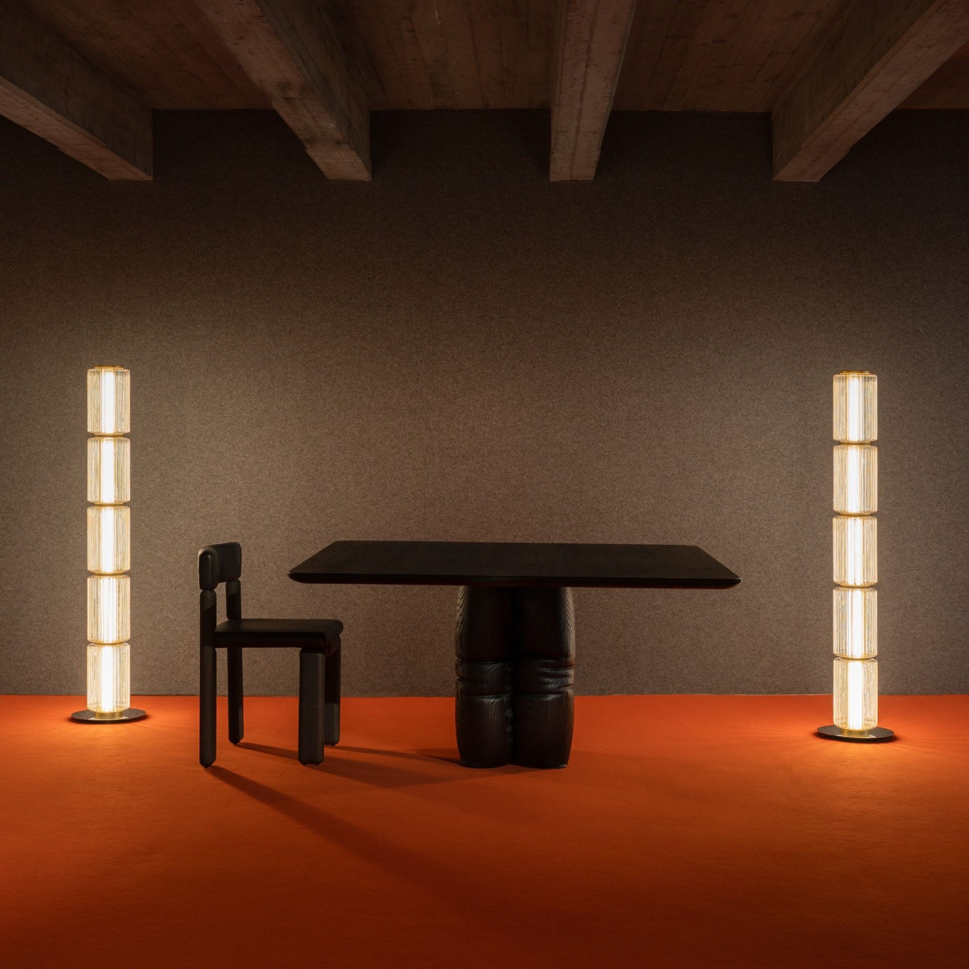 Group of tall ribbed-glass floor lamps creating soft ambient light in a dark, modern room with an orange floor.
