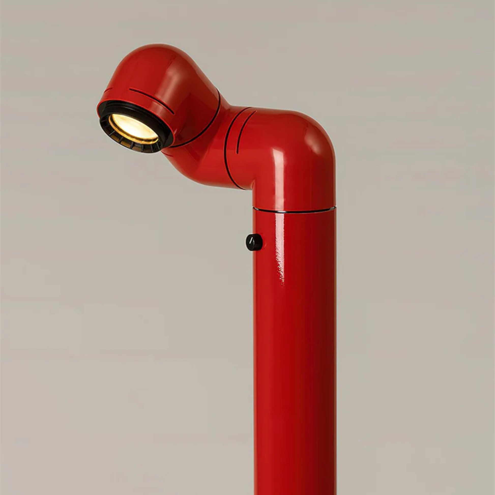 A close-up of the red floor lamp with the light focused on the floor, creating a soft glow.