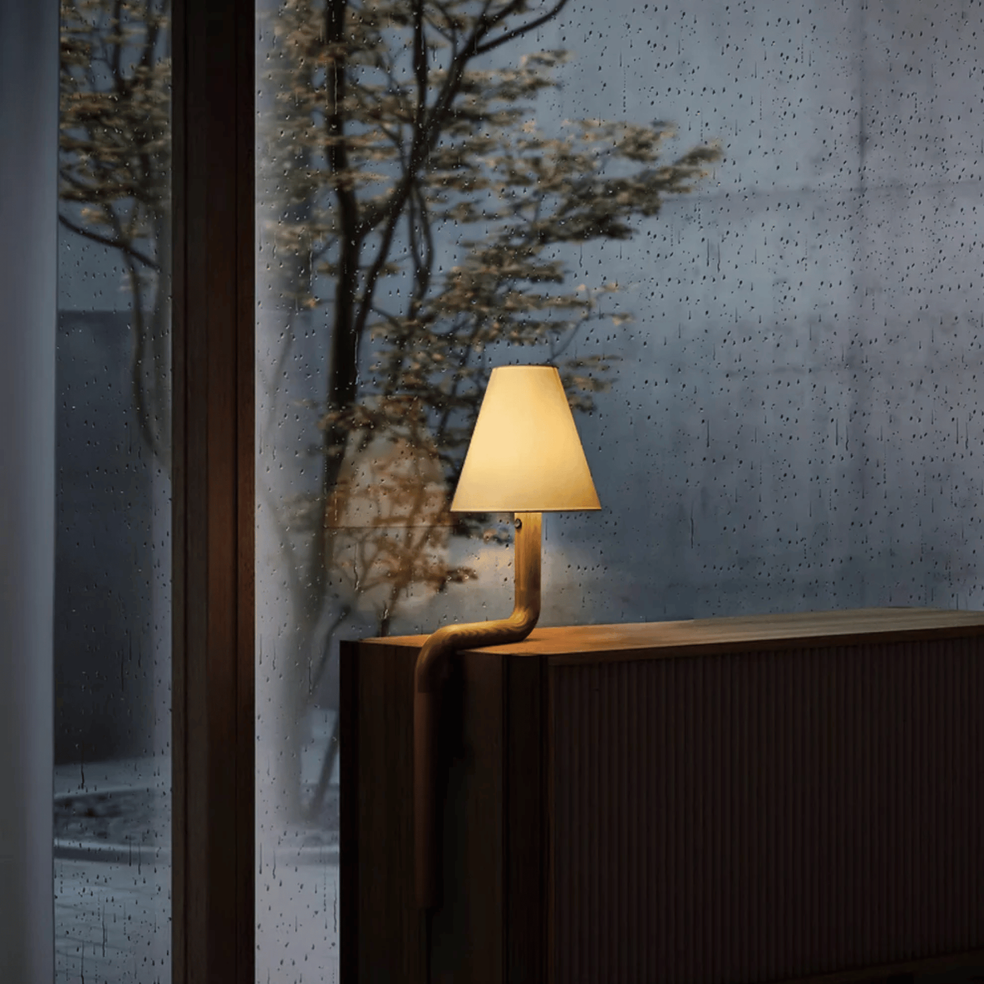 Modern lamp on a wooden surface with a textured wall and plant in the background