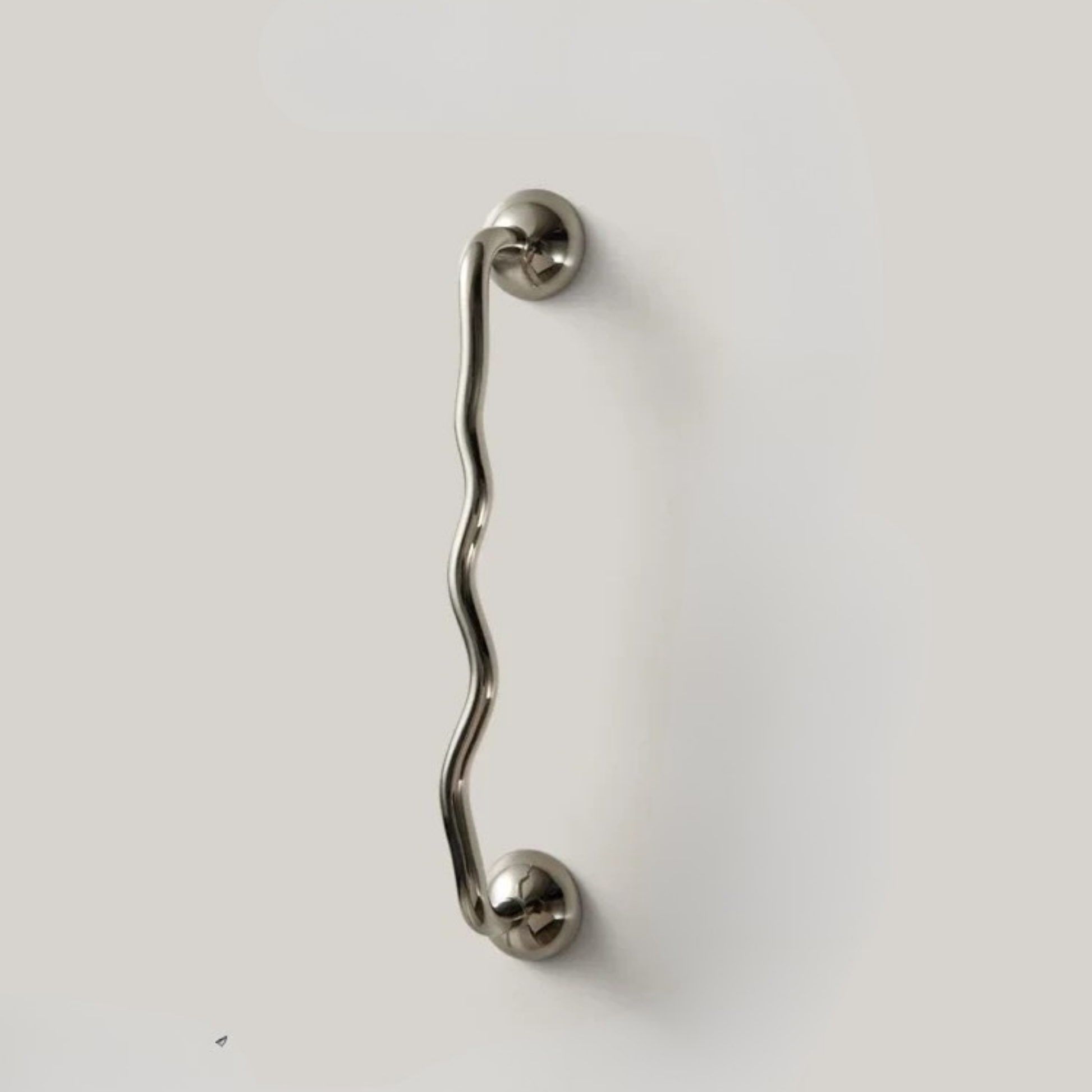 Single wavy stainless steel handle mounted on a plain light surface