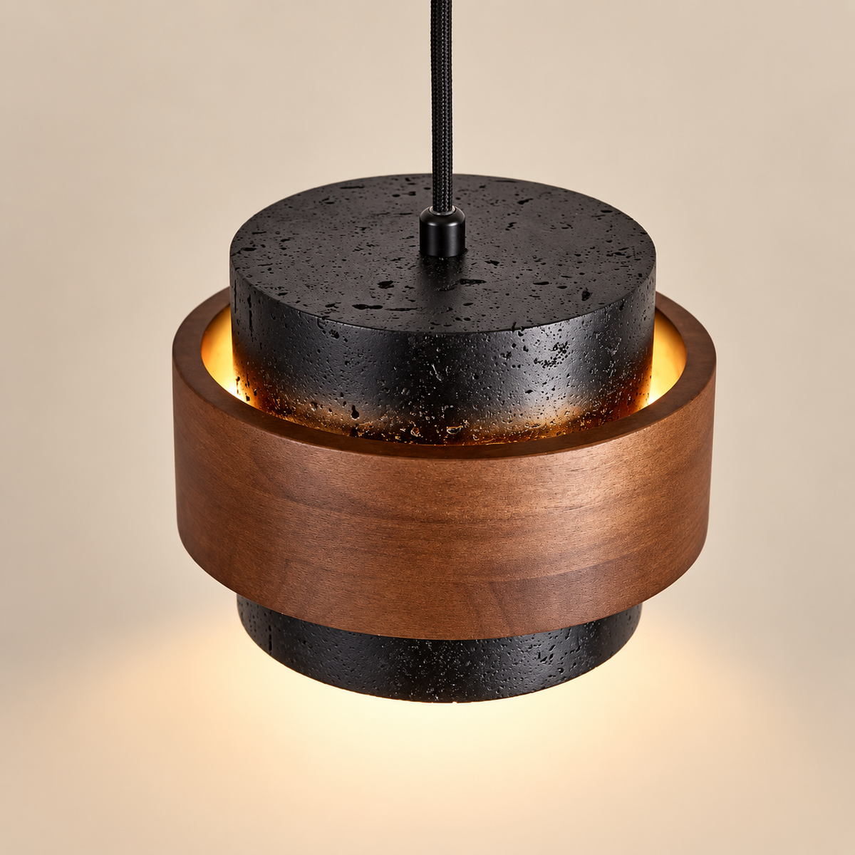 A modern pendant light fixture with a warm brown wood ring and textured black metal top and bottom, illuminated from within against a warm beige background.