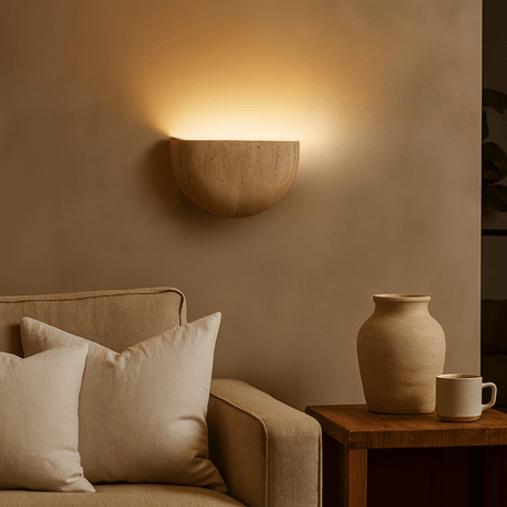 Couch with pillows, wall-mounted light fixture, and vase in a warm-toned room.
