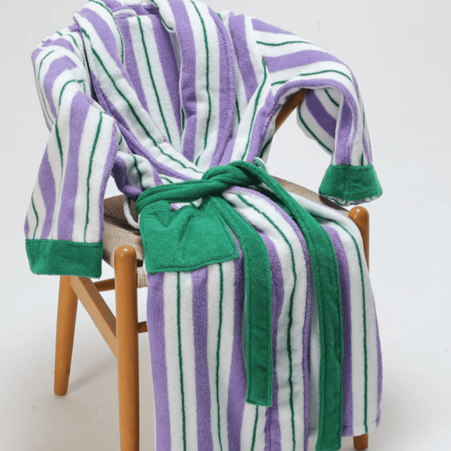 Striped robe with green trim draped over a chair on a white background
