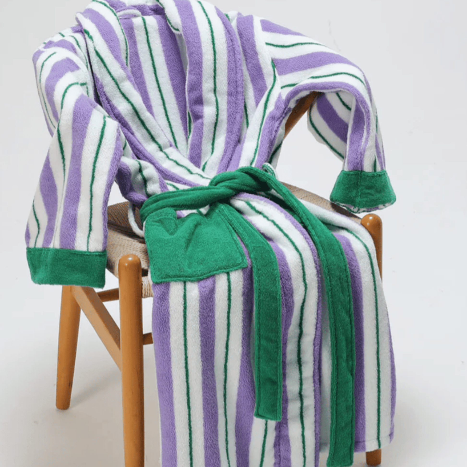 Striped robe with green trim draped over a chair on a white background