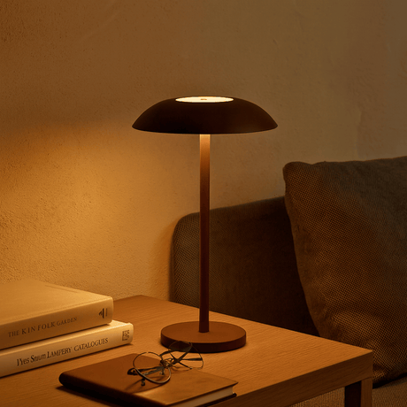 Table lamp on a wooden surface with books and glasses, warm lighting