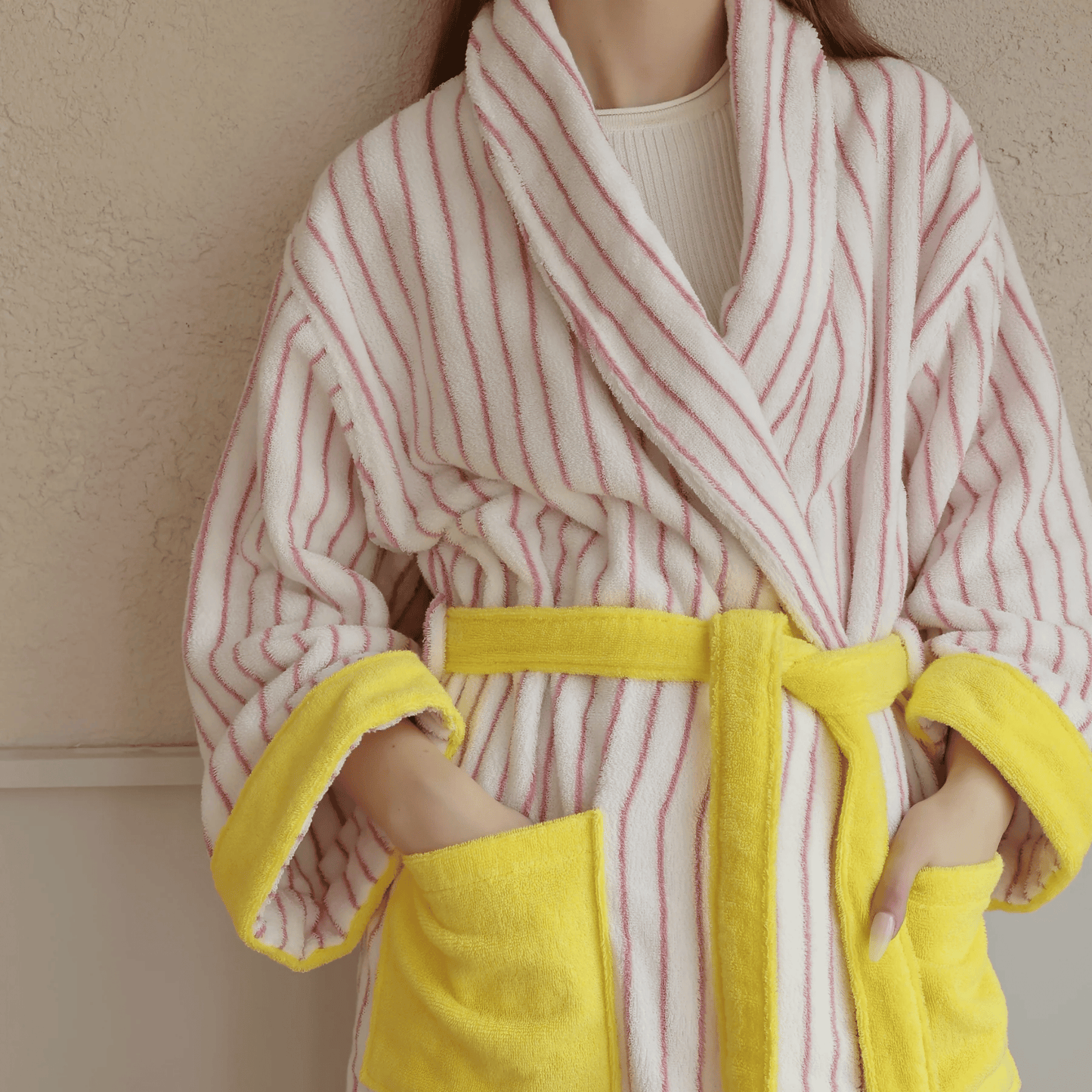 Person wearing a pink and white striped robe with yellow trim.