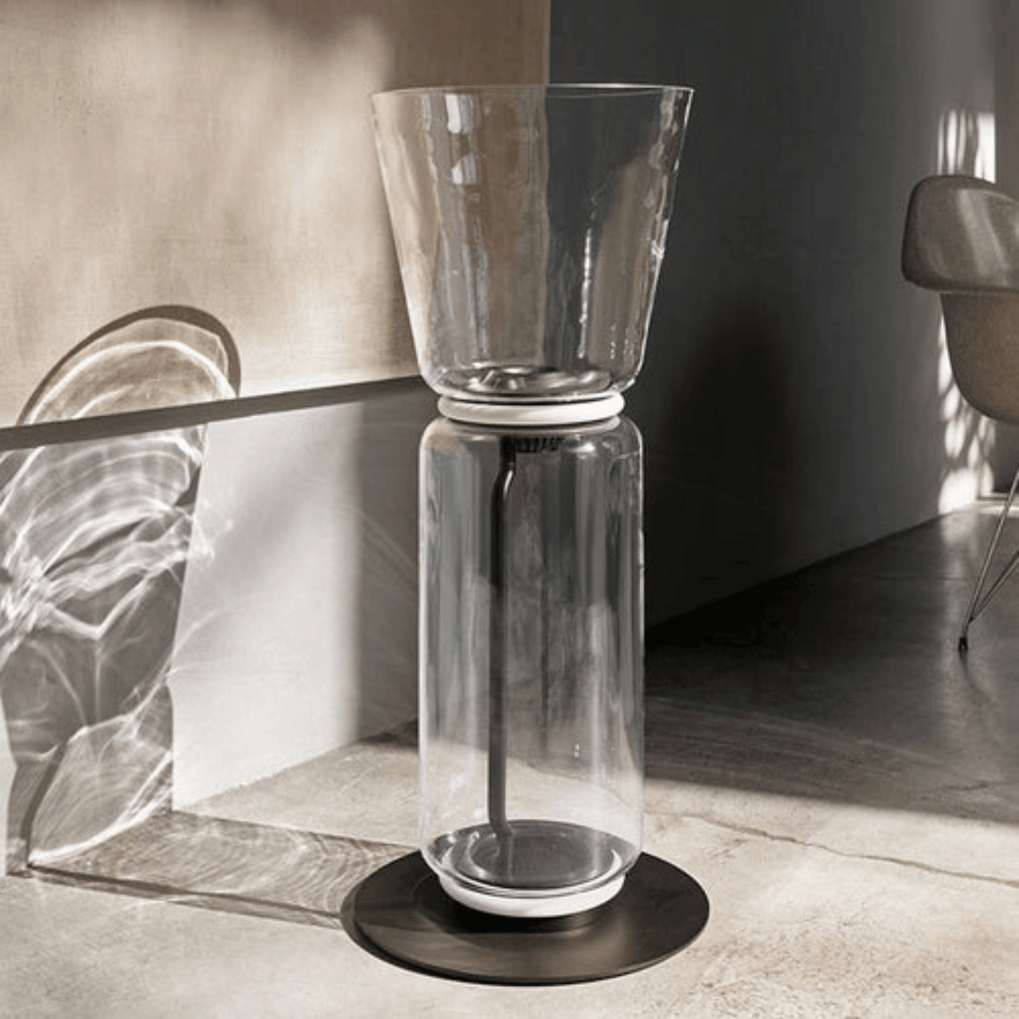 Clear glass vase with black base on a reflective surface