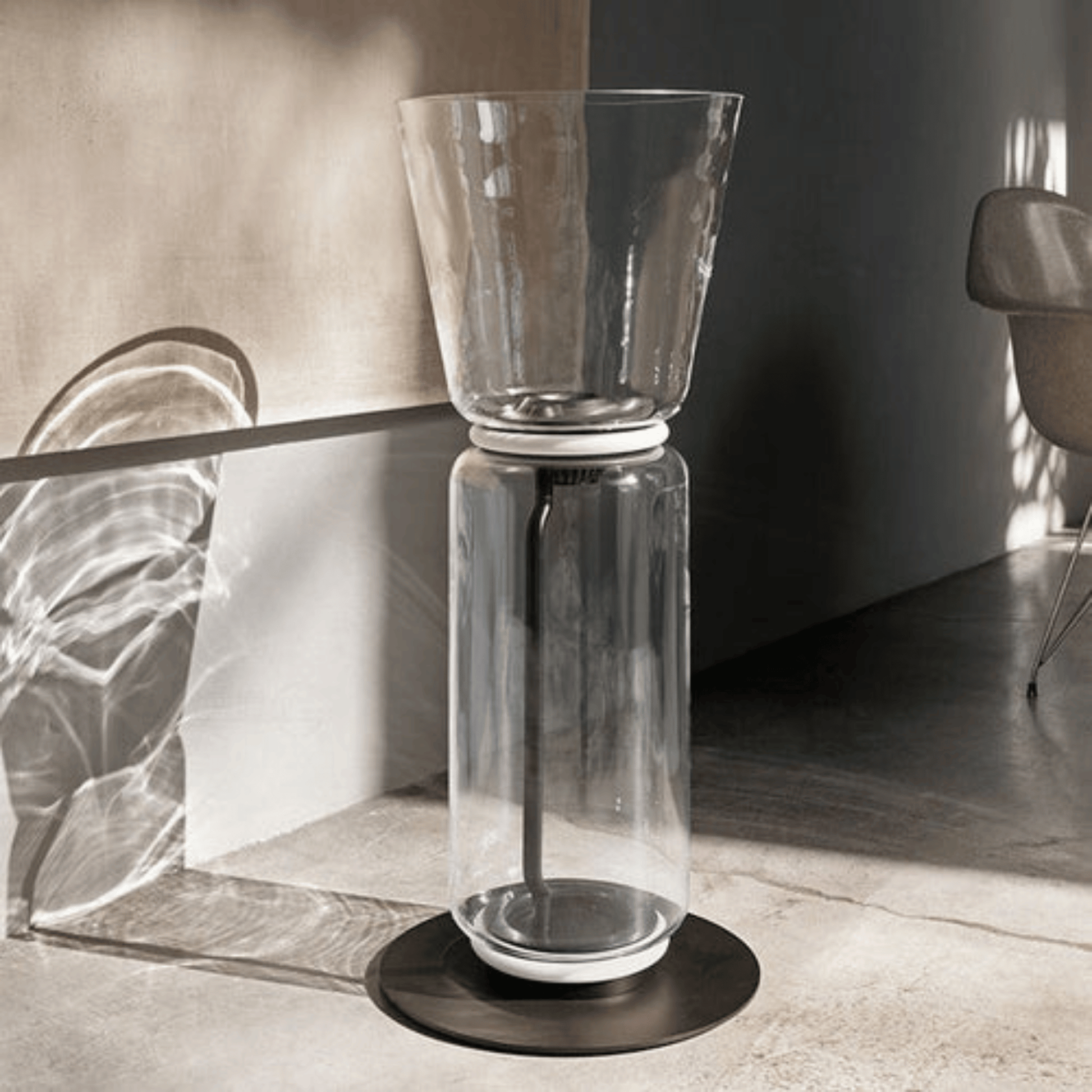 Clear glass vase with black base on a reflective surface