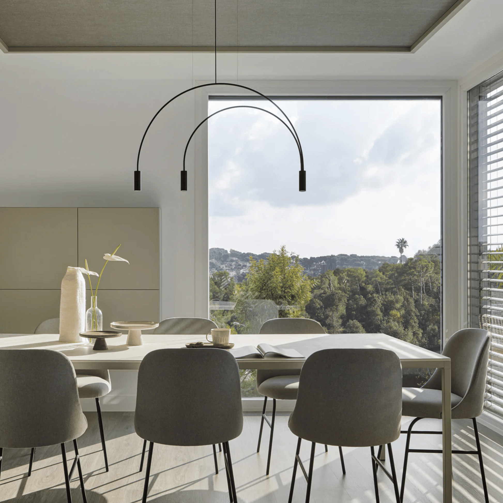 Modern dining room with a long table and chairs, featuring a stylish pendant light.