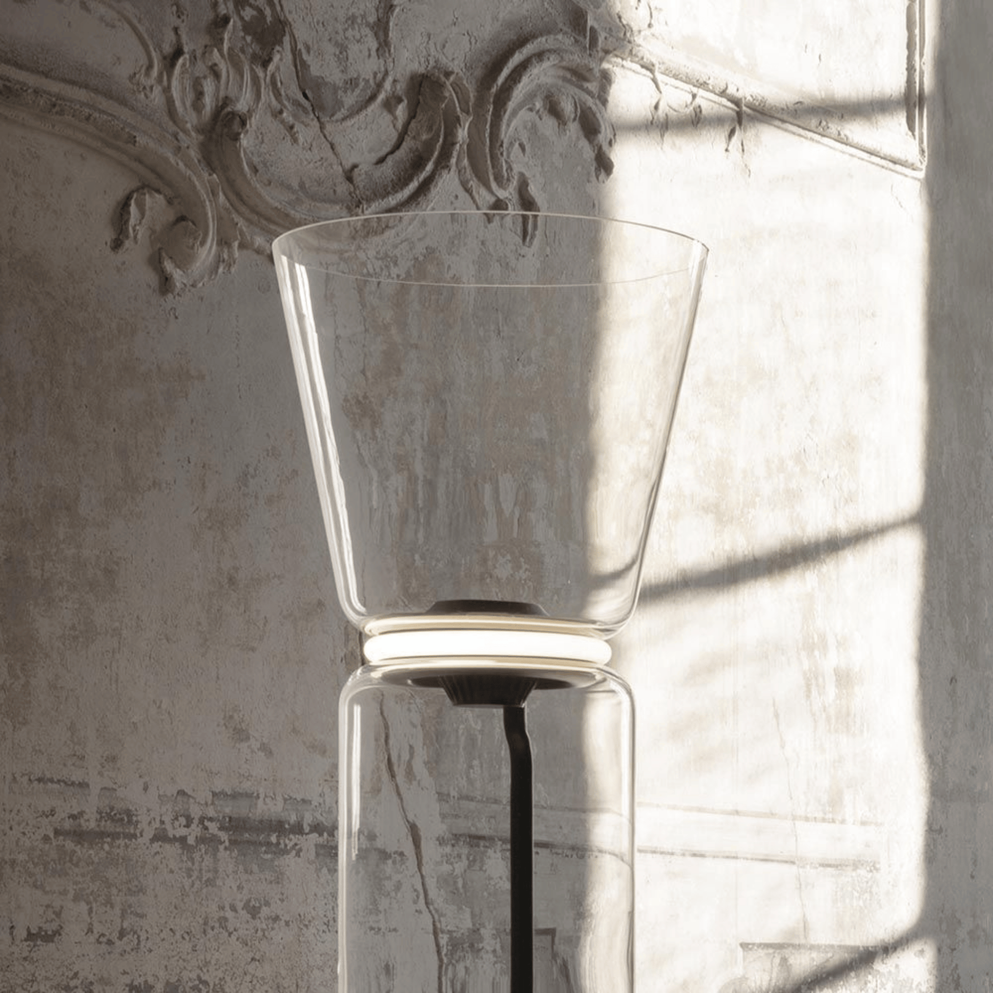 Clear glass vase against a textured wall