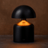 Black mushroom-shaped lamp with a warm glow on a brown background
