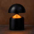 Black mushroom-shaped lamp with a warm glow on a brown background