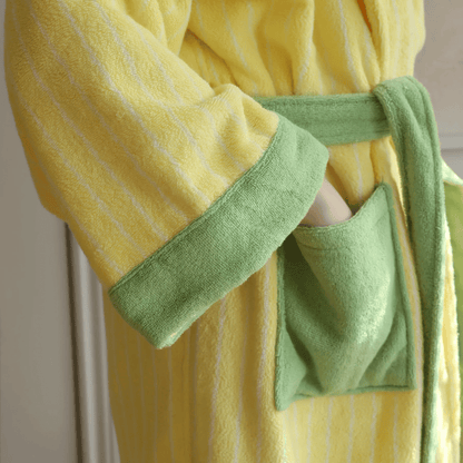 Yellow robe with green trim held by a person against a neutral background
