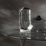 Clear glass container on a reflective surface with a dark background