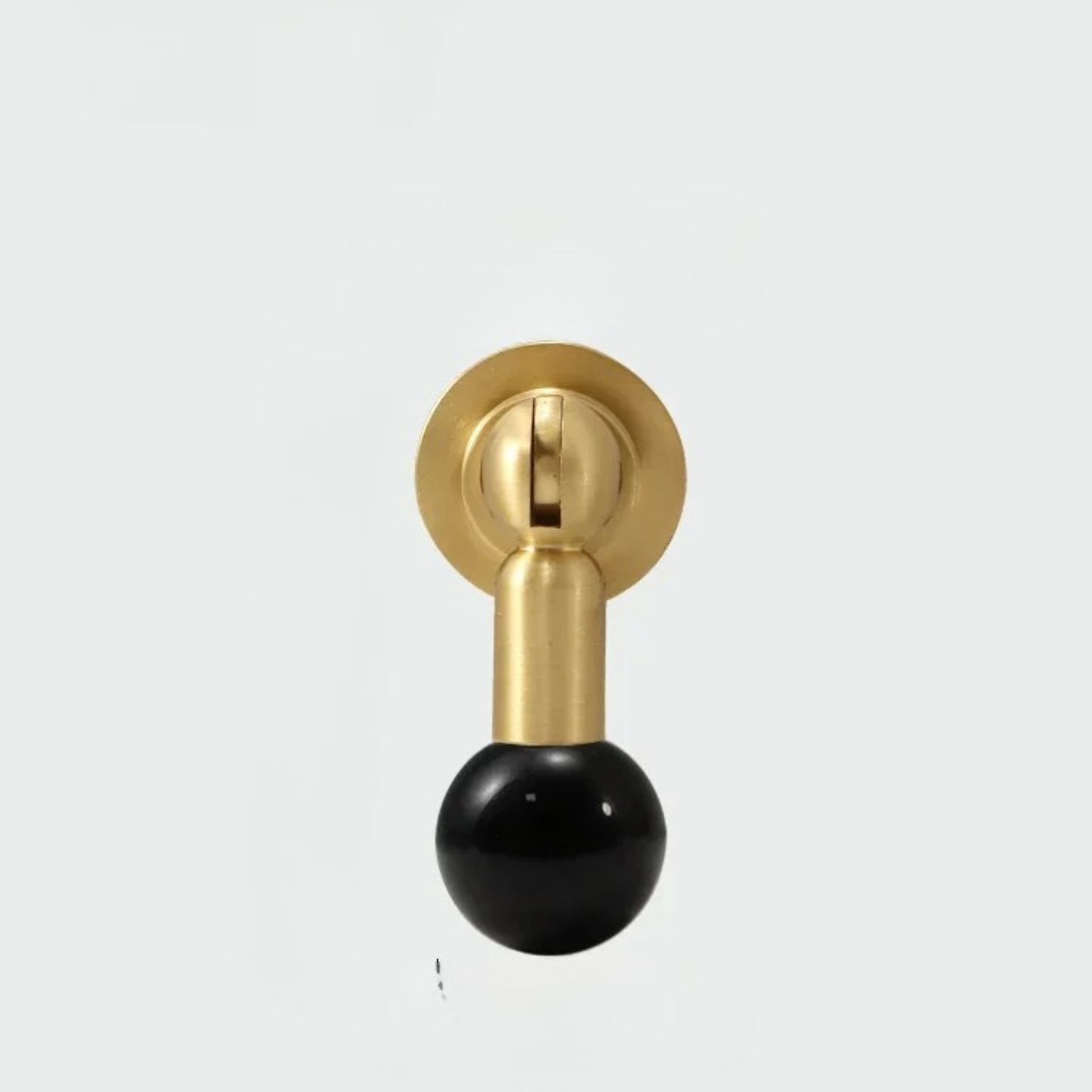 Brass cabinet knob with glossy black gemstone sphere handle on white background.