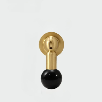 Brass cabinet knob with glossy black gemstone sphere handle on white background.