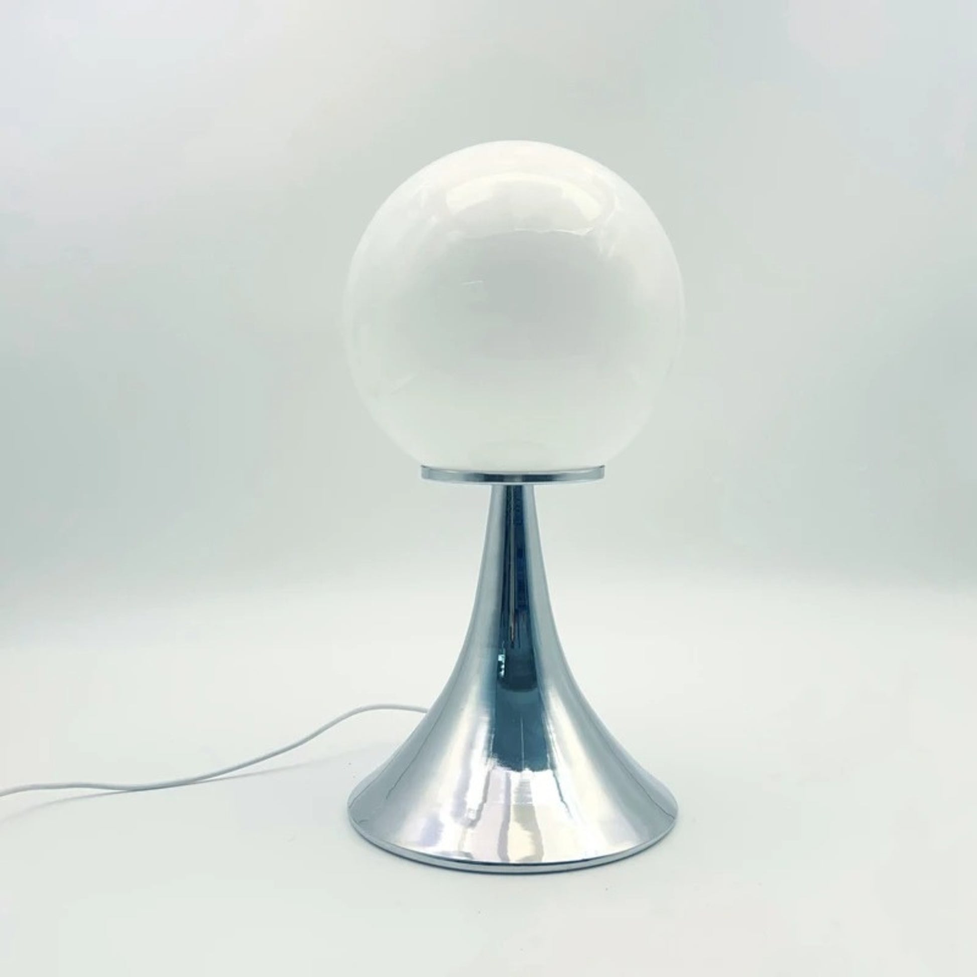 A white glass globe table lamp with a chrome base set against a minimal white background.