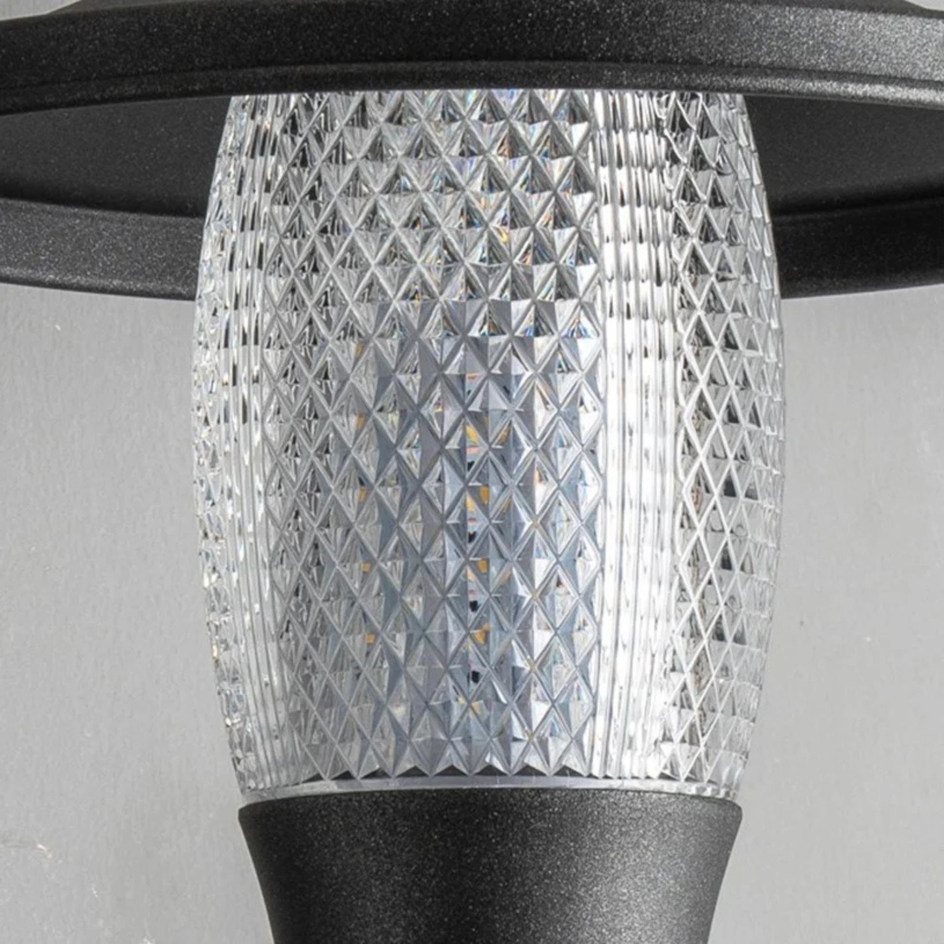 Close-up of modern outdoor light fixture showing detailed glass pattern and matte black base.
