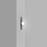 single bulb sconce with brass mount on dark raindrop textured backplate