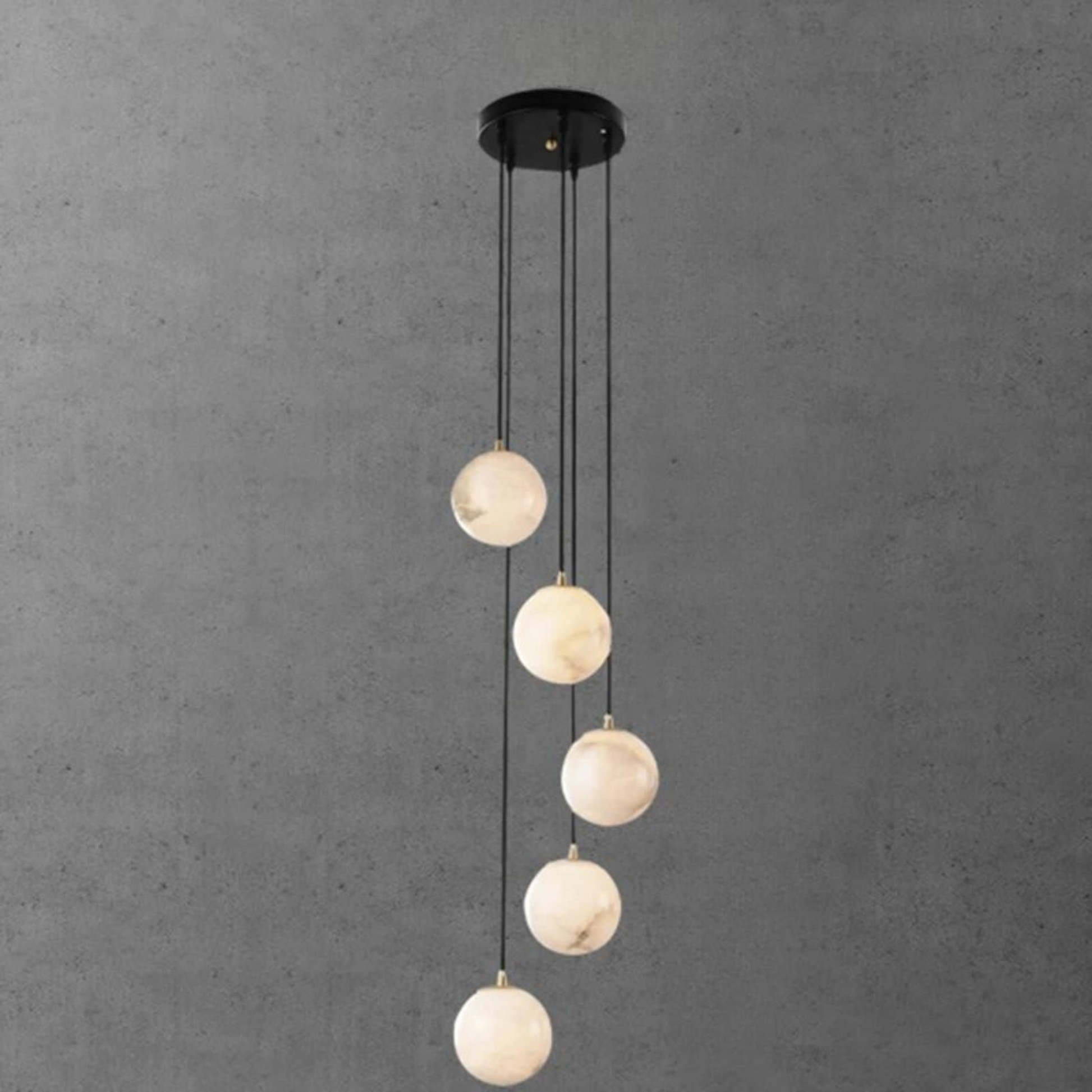 A minimalist chandelier with medium-sized glowing orbs suspended at varying heights from black cords.