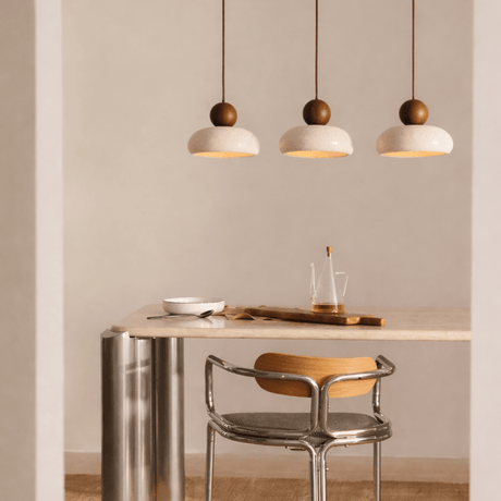 Modern dining area with a table, chair, and pendant lights in a neutral setting.