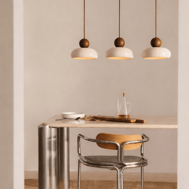 Modern dining area with a table, chair, and pendant lights in a neutral setting.