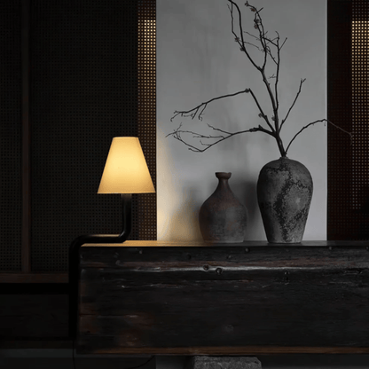 Decorative setup with a lamp, vases, and branches on a wooden surface.