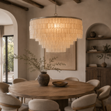Dining room with a large chandelier, round wooden table, and chairs.