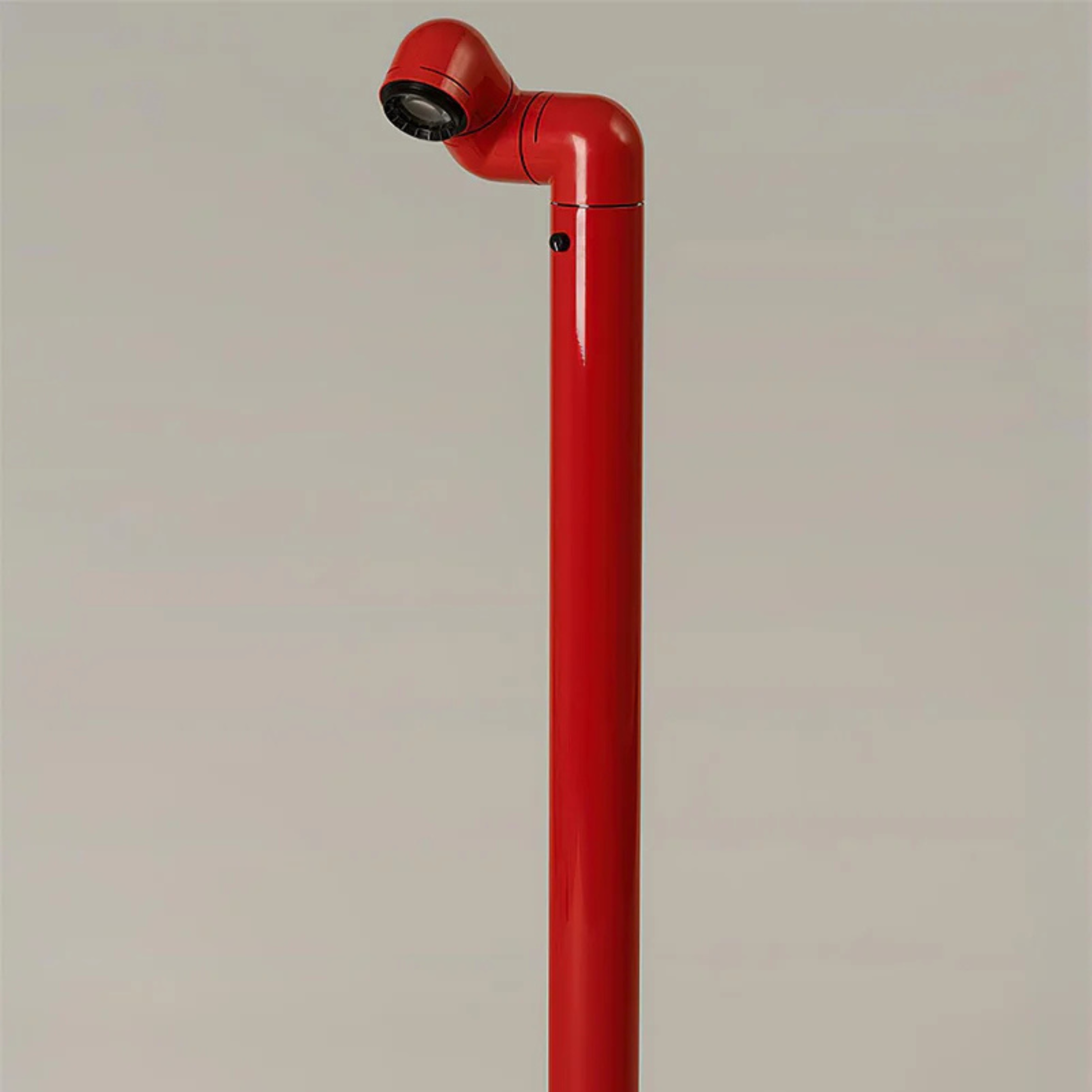 A close-up of the red floor lamp with the light focused on the floor, creating a soft glow.