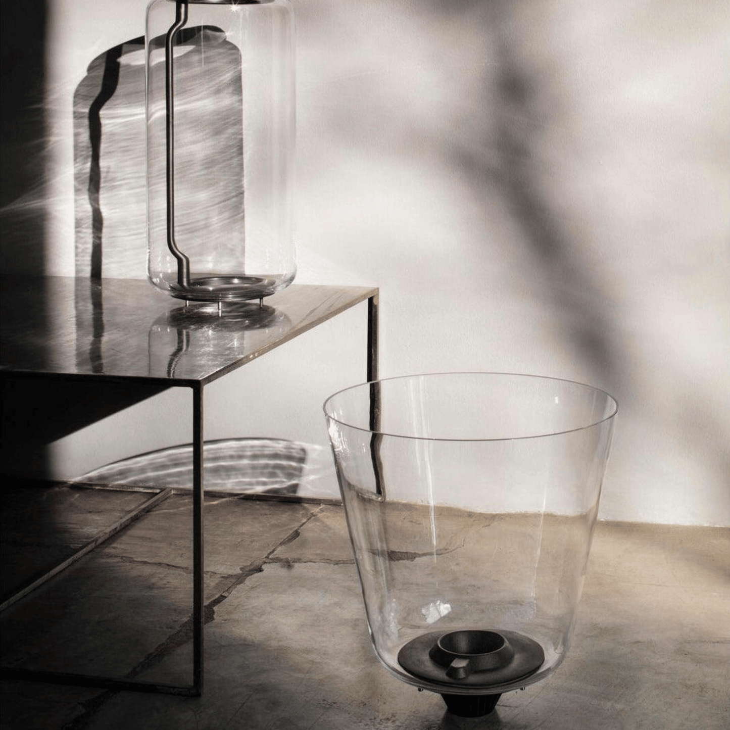 Clear glass lanterns on a reflective surface with a neutral background