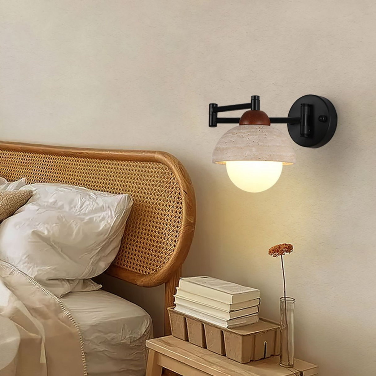 Wicker headboard with wall-mounted lamp and books on a nightstand in a bedroom setting.