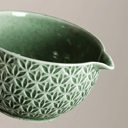 Green ceramic bowl with a geometric pattern on a beige background