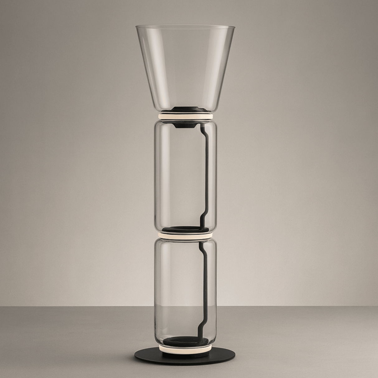Stack of three transparent glass vases on a neutral background