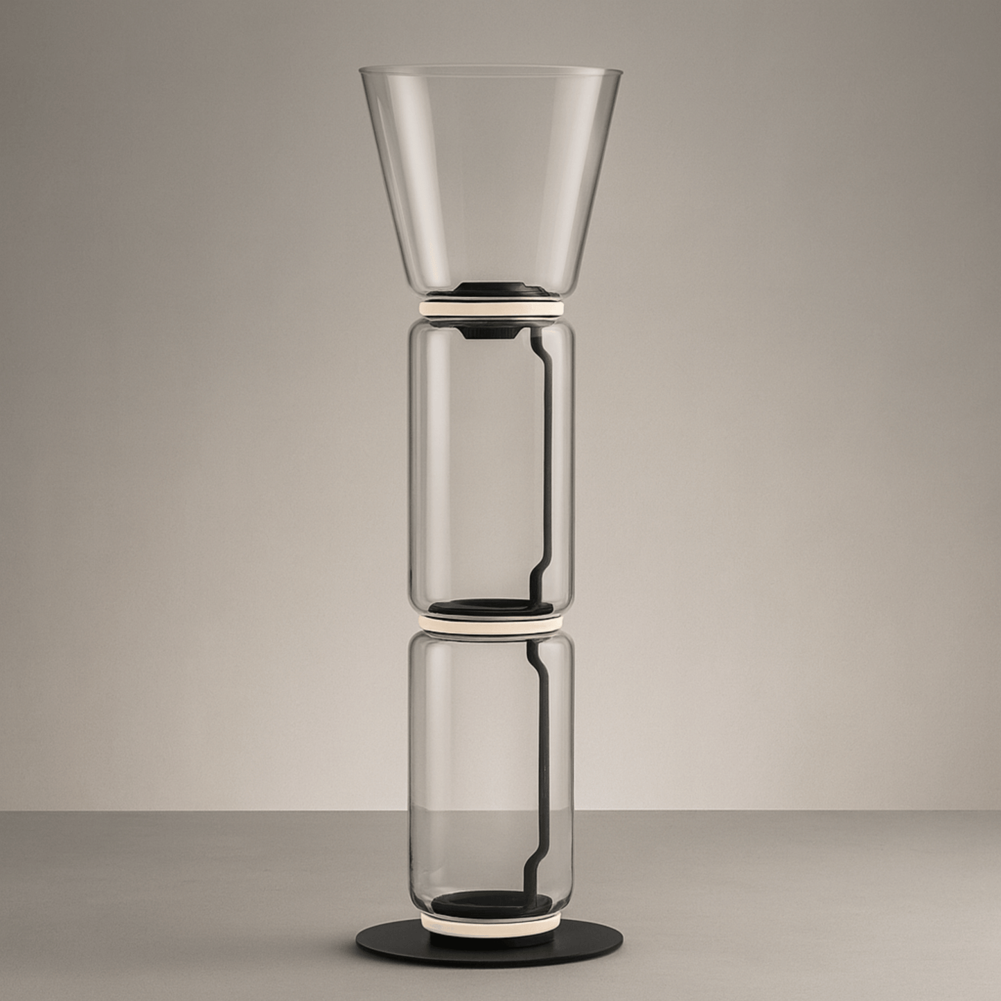 Stack of three transparent glass vases on a neutral background