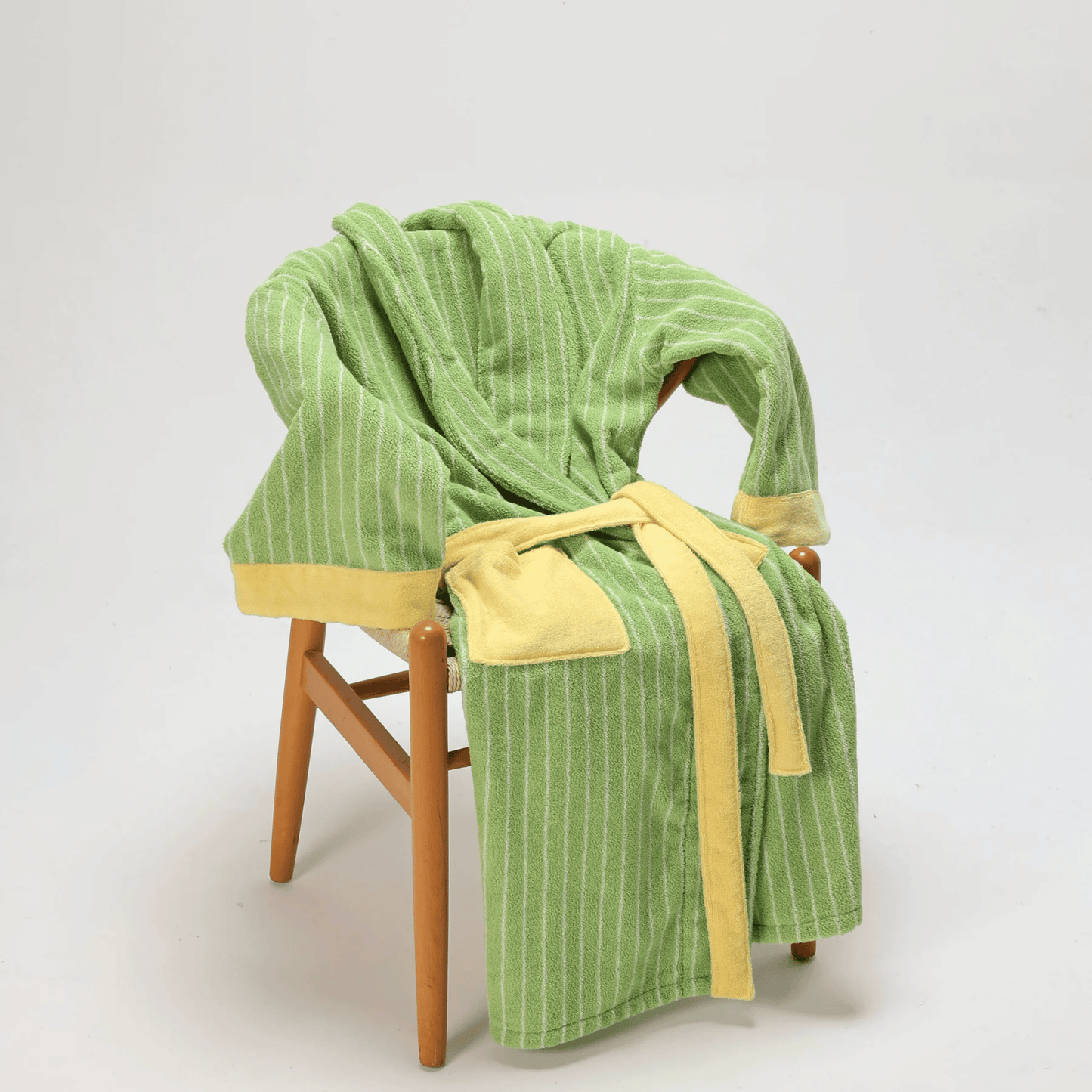 Green and yellow robe draped over a wooden chair on a white background