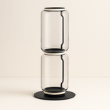 Clear glass vase with black accents on a beige background