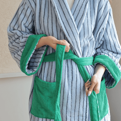 Person wearing a gray and white striped robe with green trim, holding a green towel.