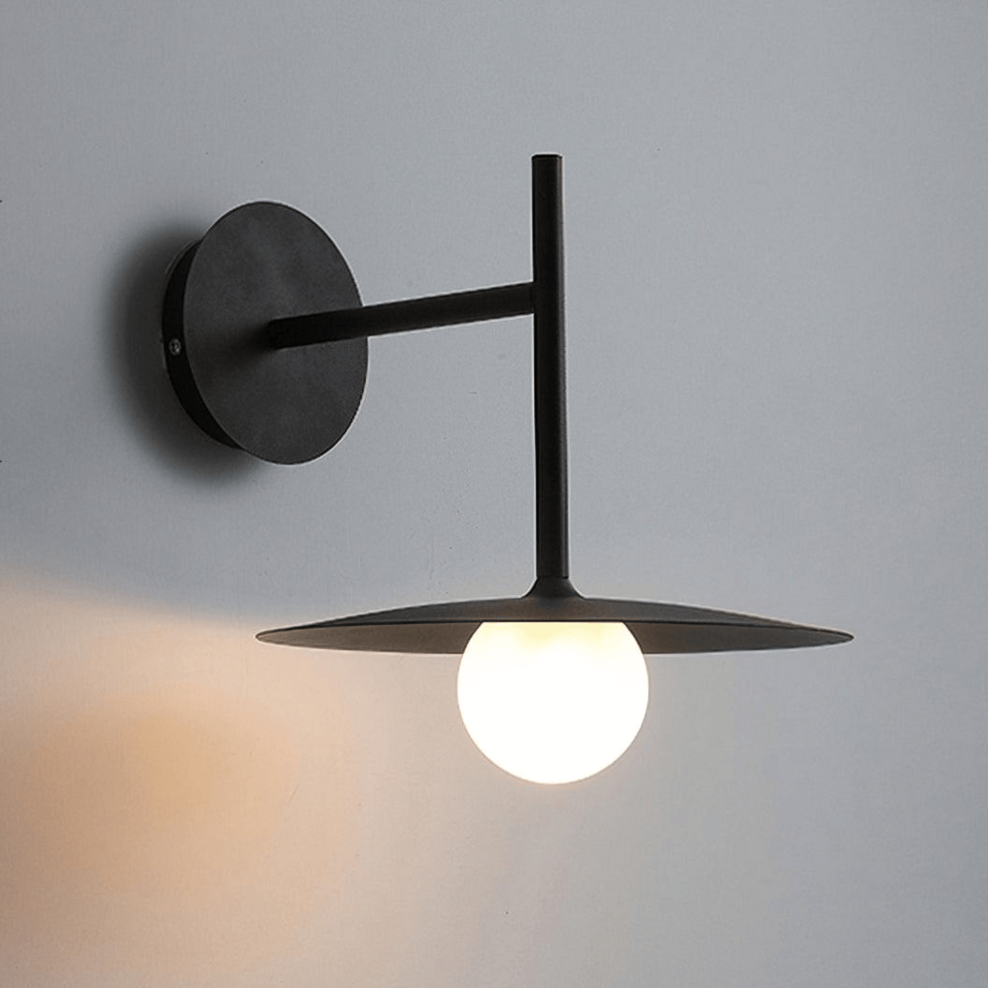 Modern wall-mounted light fixture with a single bulb on a gray background