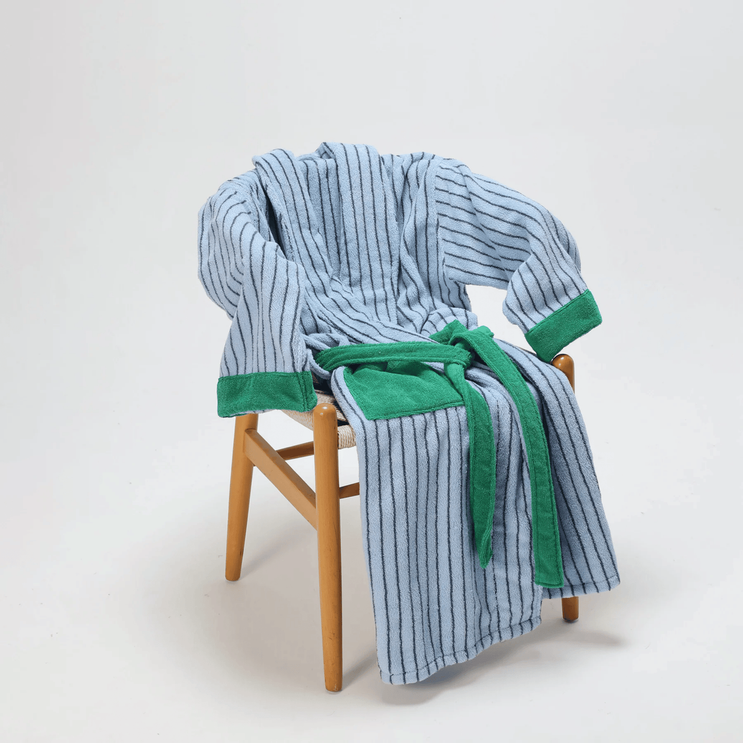 Blue and green striped robe draped over a wooden chair on a white background