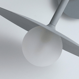 Close-up of a modern ceiling light fixture with gray blades and white sphere on a neutral background