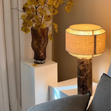 Decorative lamp with a textured base and yellow flowers in a vase on a white pedestal.