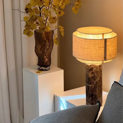 Decorative lamp with a textured base and yellow flowers in a vase on a white pedestal.