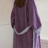 Person wearing a purple striped robe with gray trim indoors.