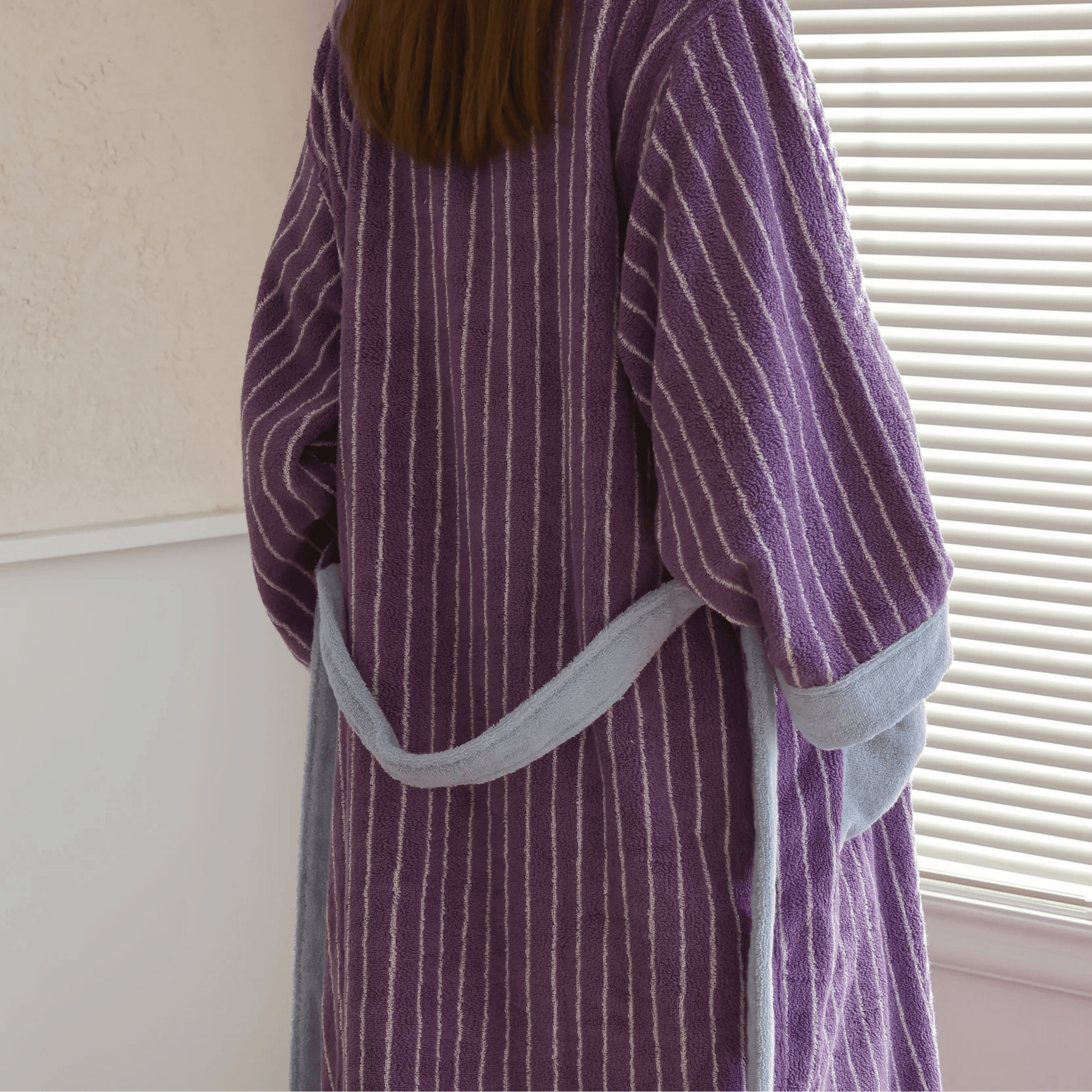 Person wearing a purple striped robe with gray trim indoors.