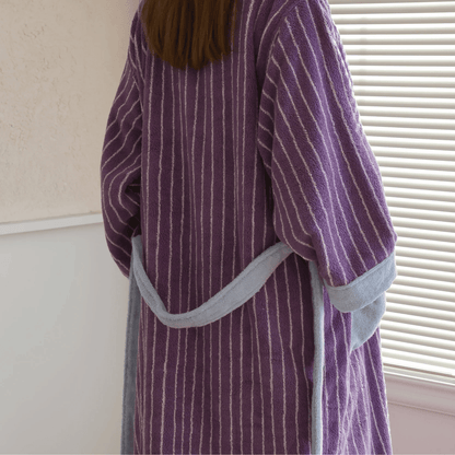 Person wearing a purple striped robe with gray trim indoors.