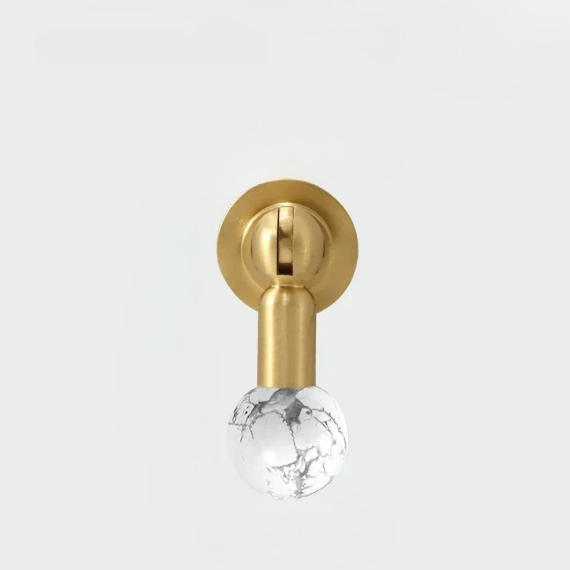 Brass knob with white marble-pattern gemstone sphere handle against a white background.