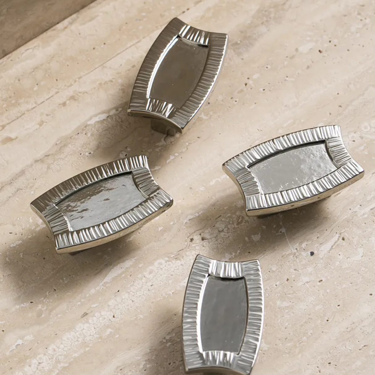 Four silver decorative mirrors on a beige surface
